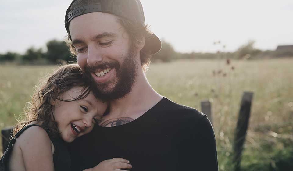 father hugs his daughter in the meadow