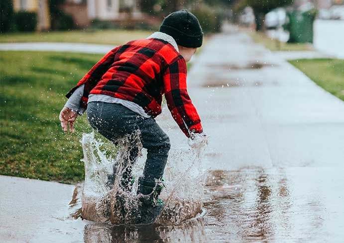  boy is jumping on a puddle