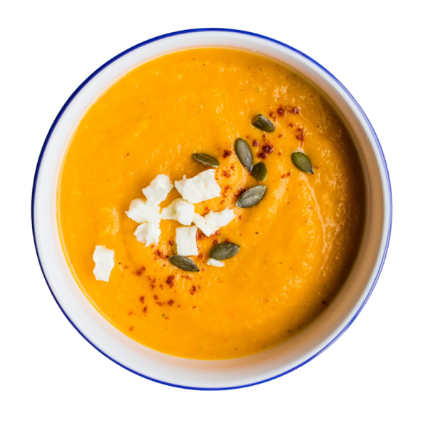a bowl of sweet potato cream soup sprinkled with pumpkin seeds and feta