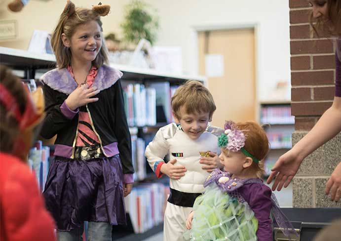 children stand and laugh, they are dressed up in fancy dress costumes