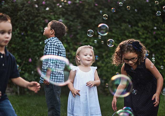 group of children catch bubbles outdoors