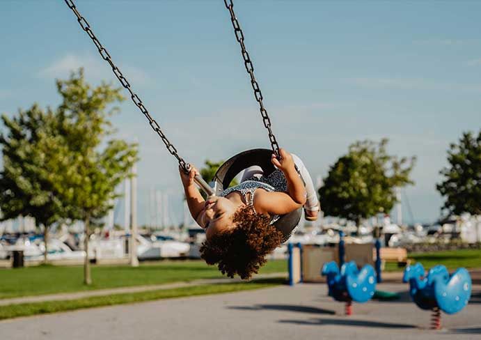little girl slings on a swing on the playground