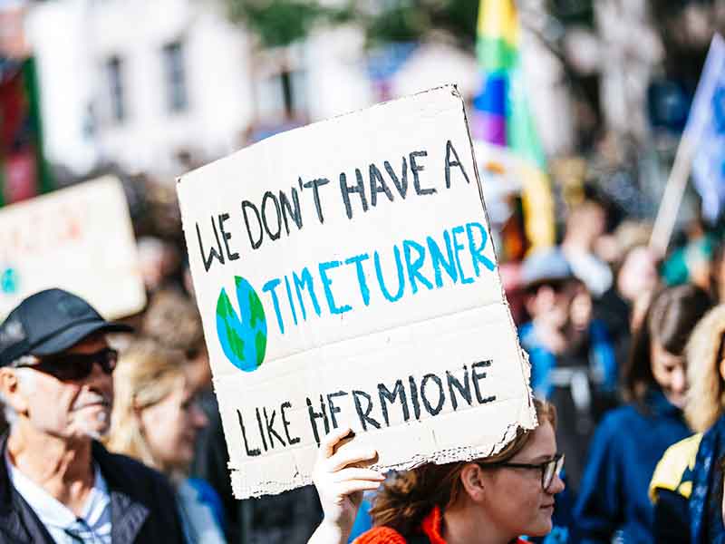  girl holds a banner with the inscription saying: we don't have o timeturner like hermione