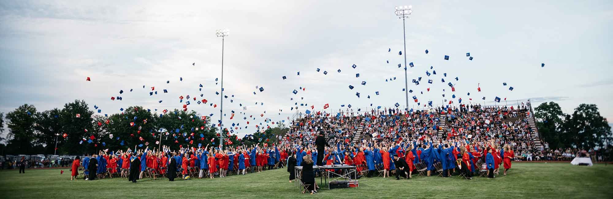  studenci wyrzucają czapki w dniu ukończenia studiów na boisku uniwersyteckim