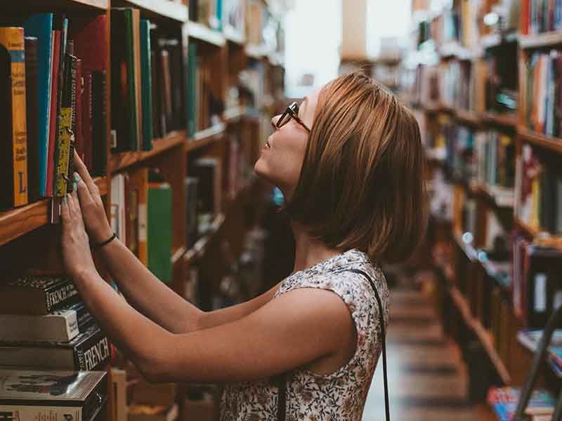 studentka poszukuje książki w bibliotece